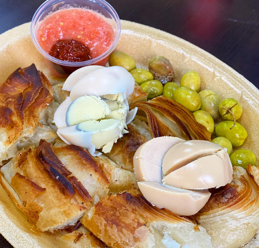 Plated burekas with pickled vegetables, egg, and tomato relish